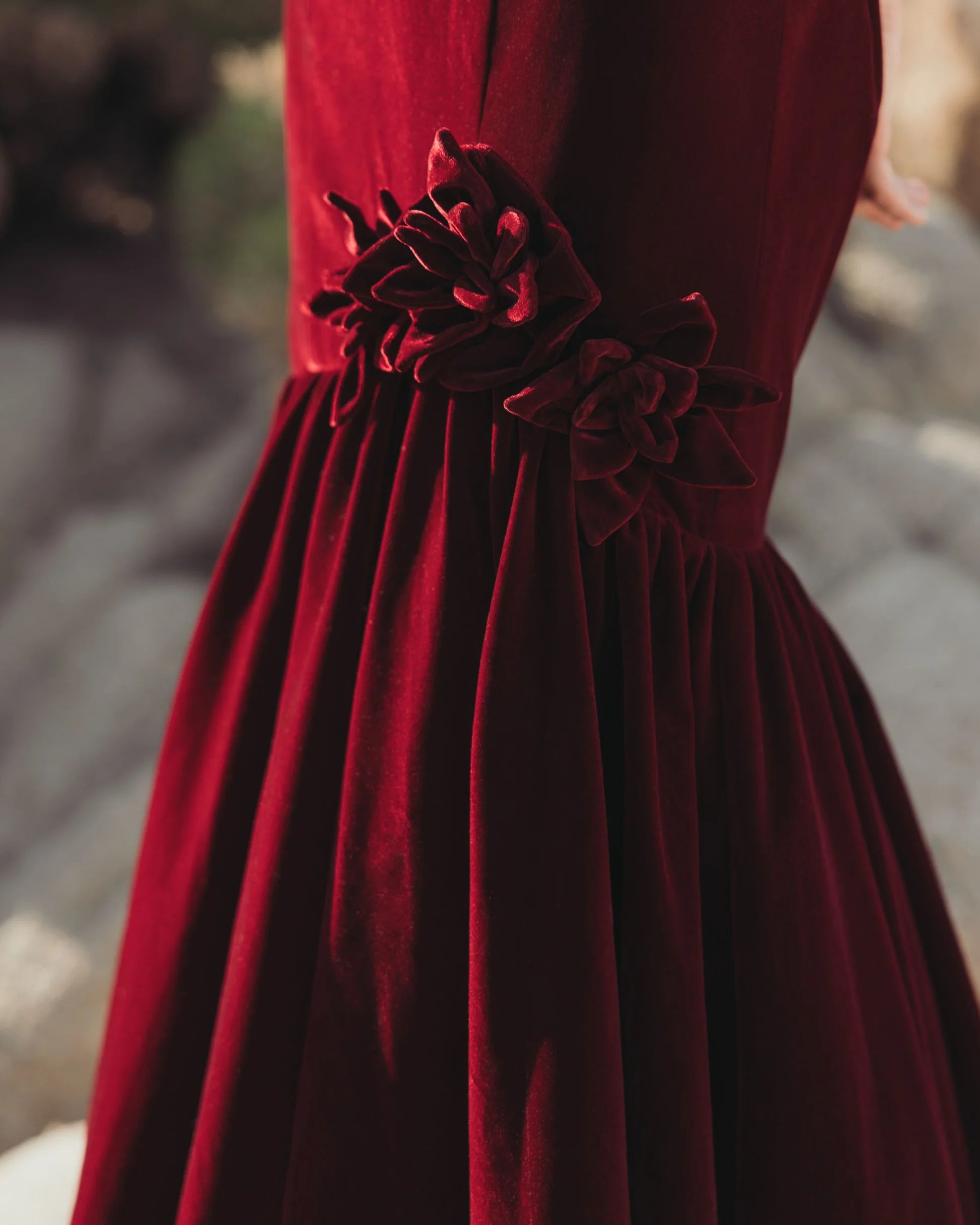 Detail of burgundy velvet mermaid gown featuring textured floral appliqué at the hip