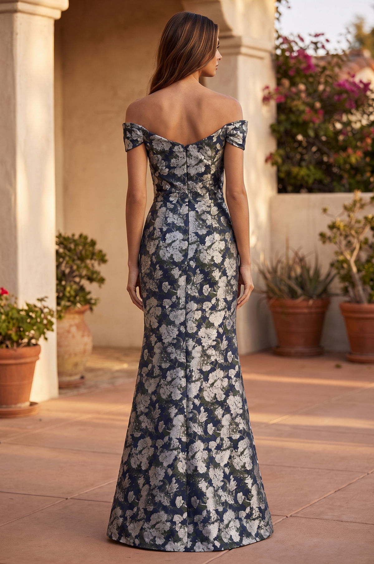 Model wearing the floor-length navy floral off-the-shoulder dress, back view