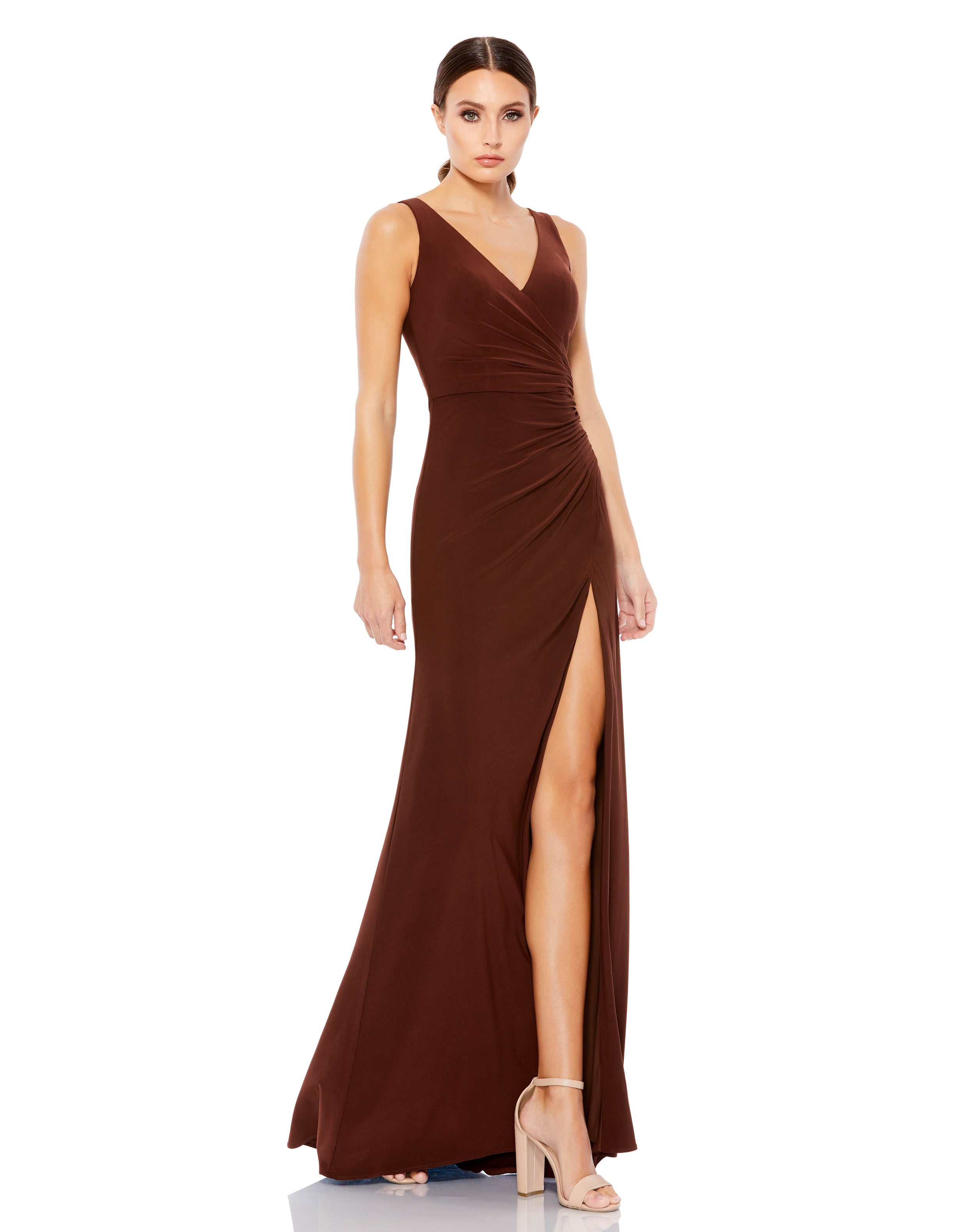 The model is wearing a Mac Duggal 26513 Prom Long Sleeveless Formal Dress with a slit.