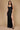 A stunning long formal low back prom dress in black, featuring a sleek silhouette that elegantly flows to the floor, showcasing a sophisticated design with a deep V-back and delicate straps.