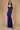 A stunning long formal low back prom dress in deep navy, featuring elegant draping and a fitted silhouette that accentuates the figure, perfect for a glamorous evening event.